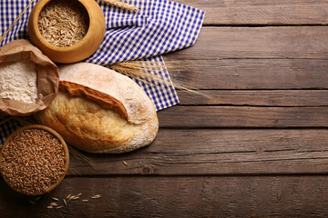 Fresh baked bread, flour, wheat and napkin on the wooden background