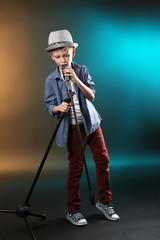 Little boy singing with microphone on a dark lighted background