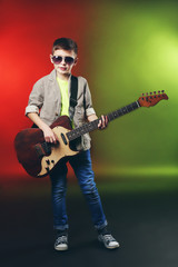 Obraz premium Little boy playing guitar on a bright background