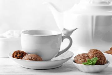 Cup of coffee with chocolate chip cookies and mint on light background