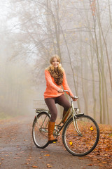 Fototapeta premium Happy active woman riding bike in autumn park.
