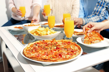 Friends hands holding hot pizza, close up