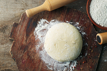 Fresh prepared dough on a wooden board, close up