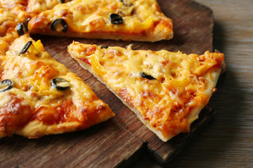 Delicious sliced pizza on wooden board, close up