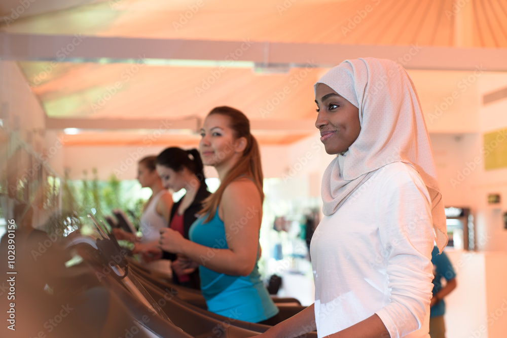 Wall mural muslim girl practicing sports in gym together with other women