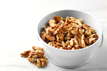 Walnut kernels in the metal bucket on white wooden background