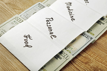 Distribution of money, financial planning, dollars in envelopes, on wooden table background
