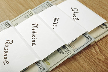 Distribution of money, financial planning, dollars in envelopes, on wooden table background