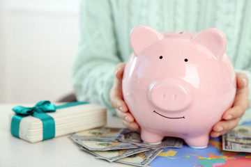 Woman holding piggy bank with dollar banknotes. Savings money for gifts concept