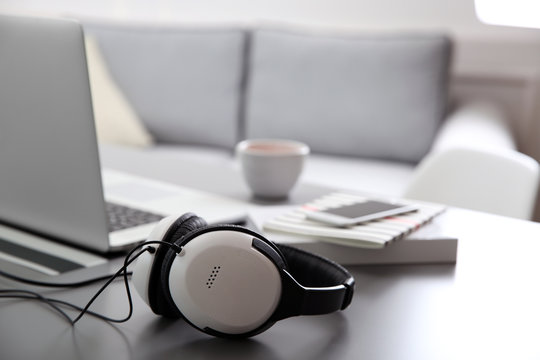 Headphones, phone and laptop on white table against defocused background