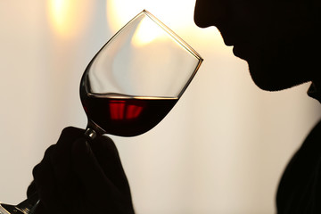 Silhouette of man sniffing red wine in a glass, close up