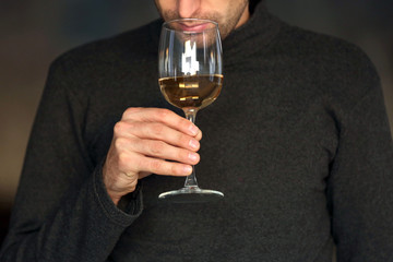 Man sniffing white wine in a glass, close up