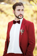Portrait of the groom, red suit with a buttonhole flower. Wedding in style Marsala color.