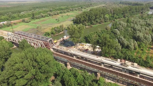 Aerial view on workers with heavy machines working on bridge railway reconstruction.
