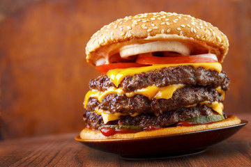 Big beef burger with three patties and cheese on plate , wood background - 102891705