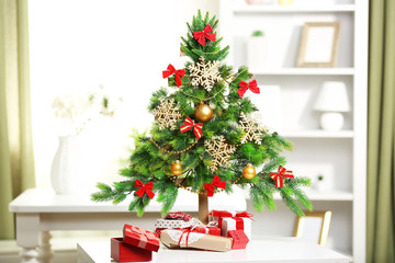 A handmade green Christmas tree and presents on the table, in the room