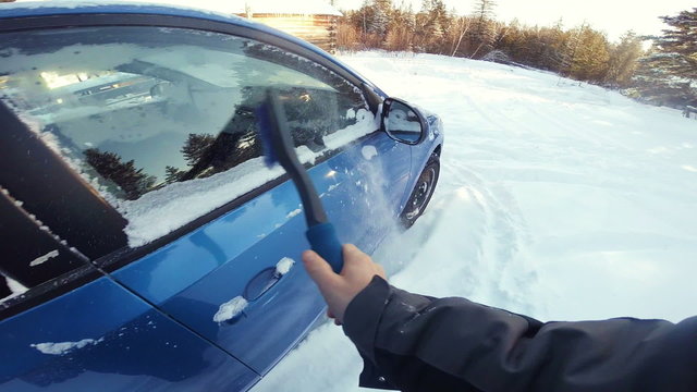 POV of a Man Removing Snow of his Blue Car
