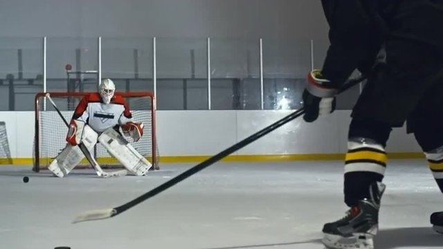 Hockey player striking pucks with his stick and goaltender catching all of them