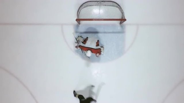 Directly above view of forward and goaltender playing hockey