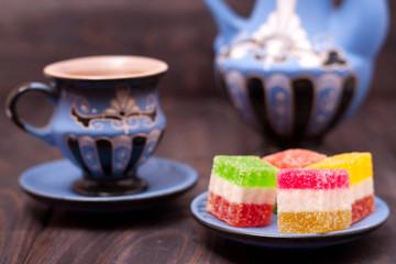 fruit jelly on wooden background with cup of tea