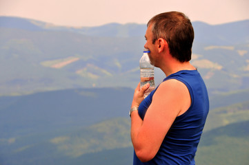 Fototapeta na wymiar A man with a bottle of water on the mountain