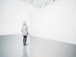 Photo of girl in modern gallery looking at the blank canvas. 