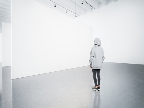 Young woman in modern gallery looking at the blank canvas. 
