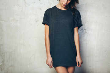 Young girl wearing blank black t-shirt. Concrete wall background. Horizontal