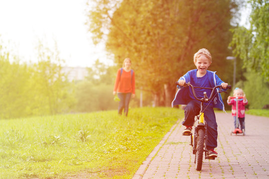 happy kids riding scooter and bike in the park