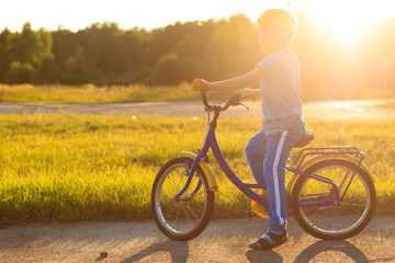 Obraz premium little boy riding bike at sunset, kids sport