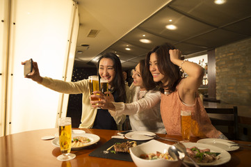 Three women are taking place that are raised in a bar in the smartphone