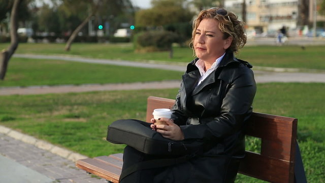 Portrait of happy middle age business woman during break outdoor, resting and relaxing on the city park bench