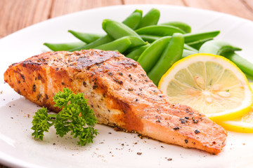 Grilled salmon with lemon, green bean and herb, on white dish. Dinner concept