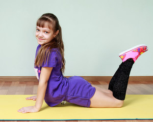 Cute girl  in violet sports costume is bending at the waist, smi