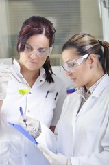 Attractive young PhD student scientist observing the green indicator color shift after the solution destillation in chemical laboratory 