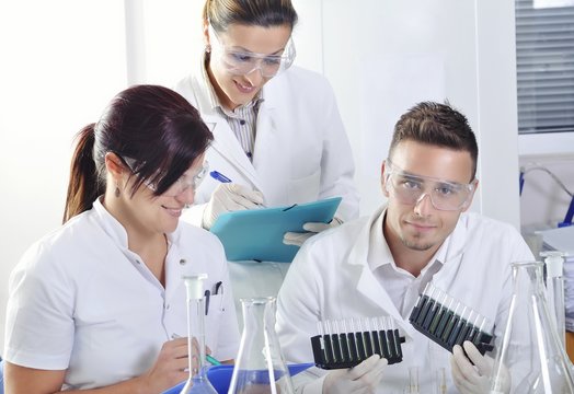 Attractive young PhD students scientists  observing the blue, yellow and green indicator color shift after the solution destillation in chemical laboratory 