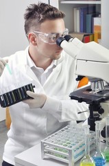 Young scientist studying new substance or virus in microscope