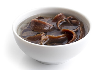 Anchovy fillets in oil in a white bowl isolated on white in perspective.