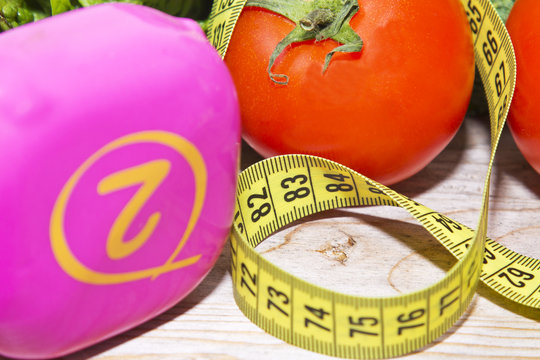 tape measure with tomatoes, vegetables and dumbbells