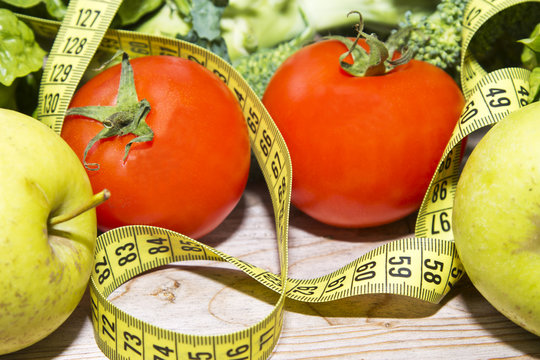 tape measure with tomatoes, vegetables and apples