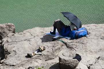 Elderly man is resting on a rock