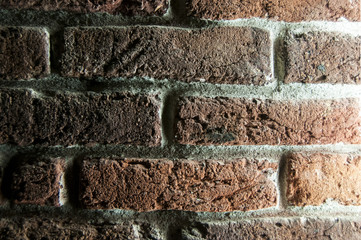 Brick wall illuminated with side artificial lighting closeup as background