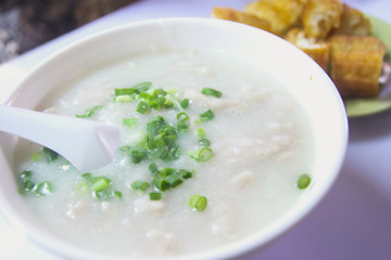 Rice porridge, or jook with boiled quail eggs in pink bowl