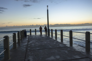 Swimmers Silhouetted Pier dawn ocean morning exercise .