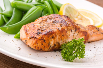 Grilled salmon with lemon, green bean and herb, on white dish. Dinner concept