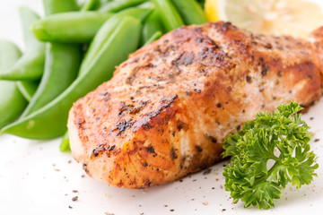 Grilled salmon with lemon, green bean and herb, on white dish. Dinner concept