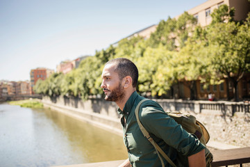 Handsome bearded man walking on bridge and looking away