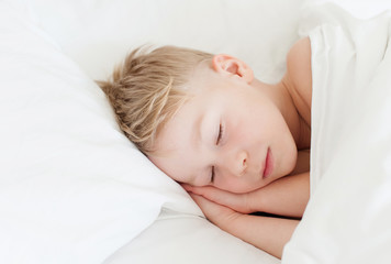 Obraz na płótnie Canvas boy sleeping in white bed