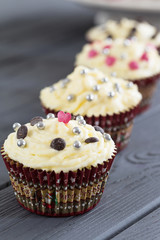 Row of Red Velvet Valentines Day Cupcakes with Sprinkles over White on Dark Grey Background, Vertical