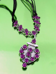 Silver fashion jewelry with purple rhinestones on green mirrorlike background